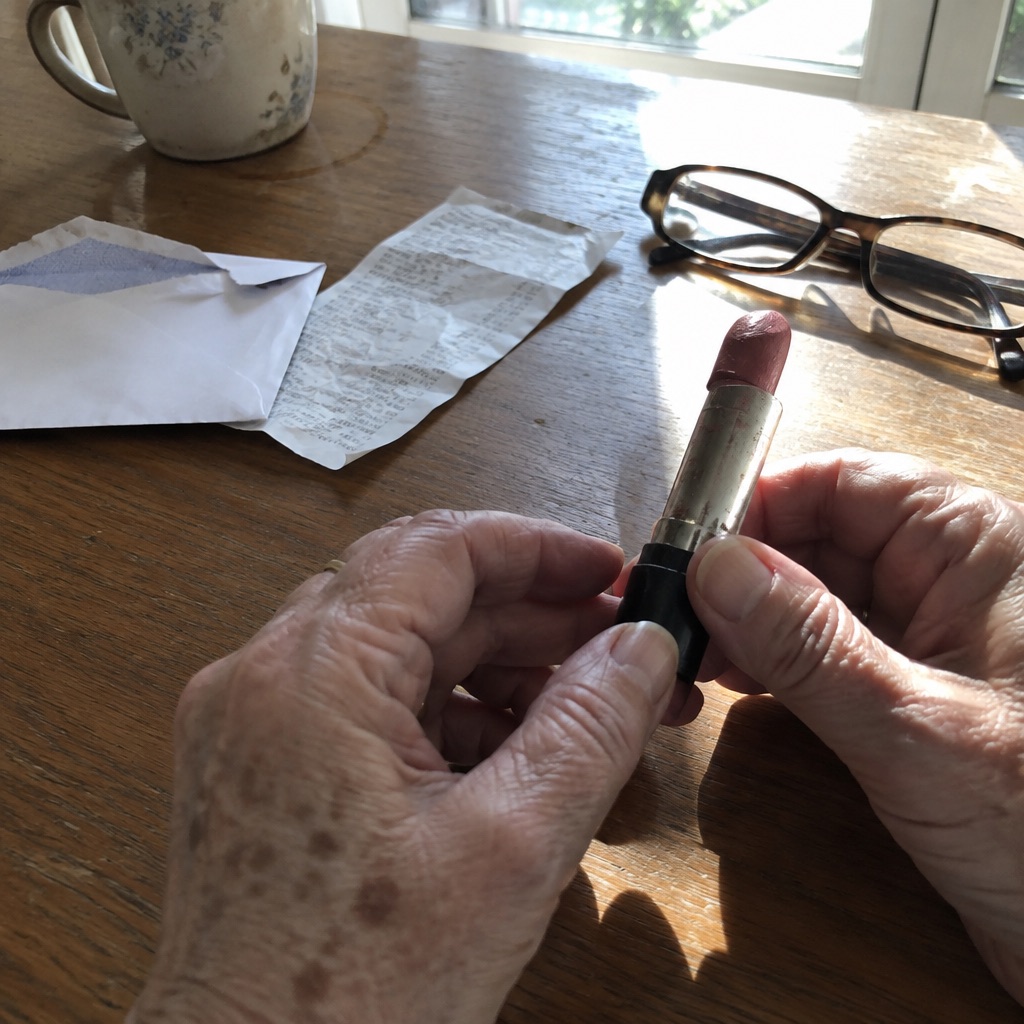 The hands of an older woman holding a worn lipstick tube